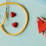 A stethoscope, blue medical mask and some red paper hearts are laid out on a table as a display of gratitude