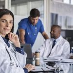 Group of smiling doctors around a conference table demonstrating physician satisfaction